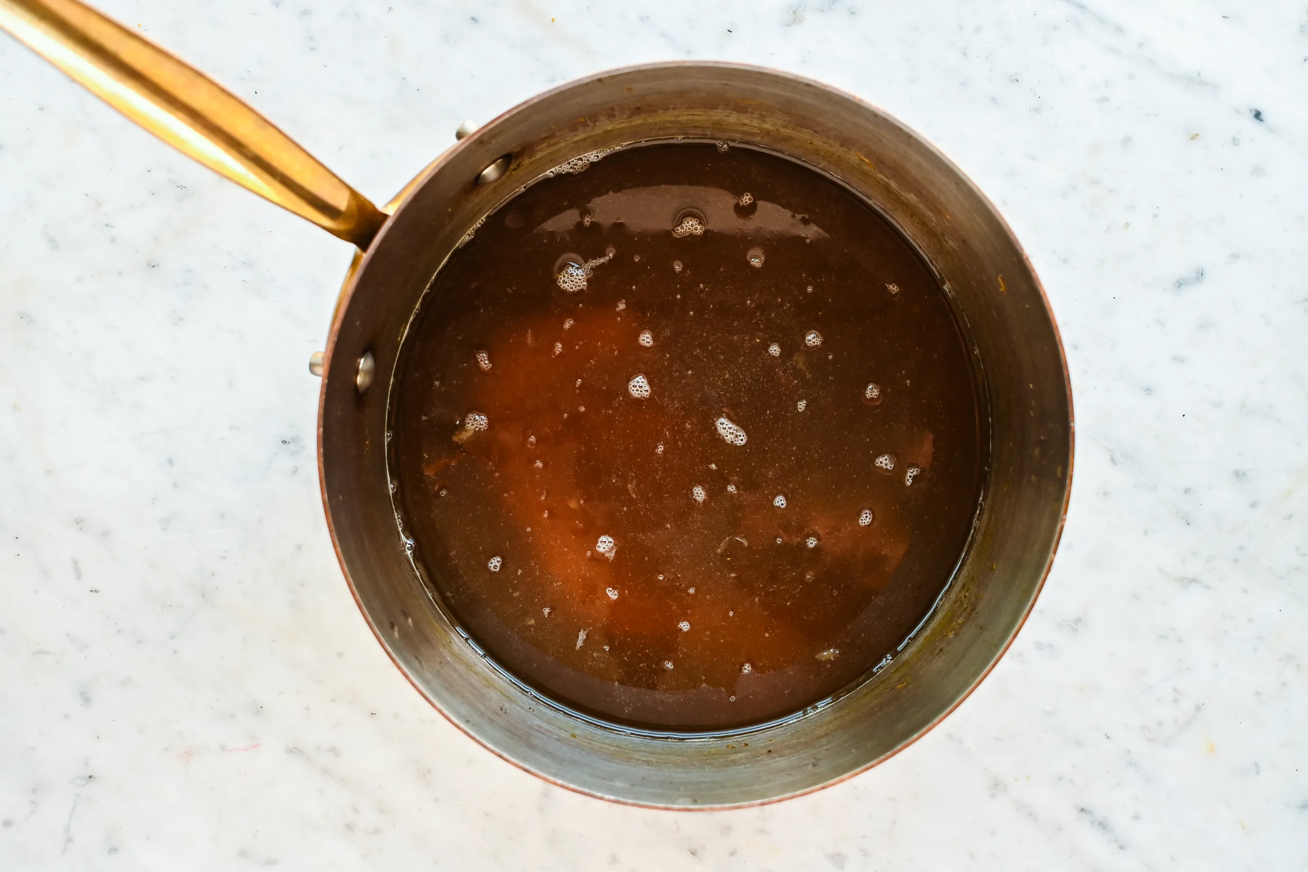 Dandelion syrup simmering in a saucepan while making homemade dandelion honey.