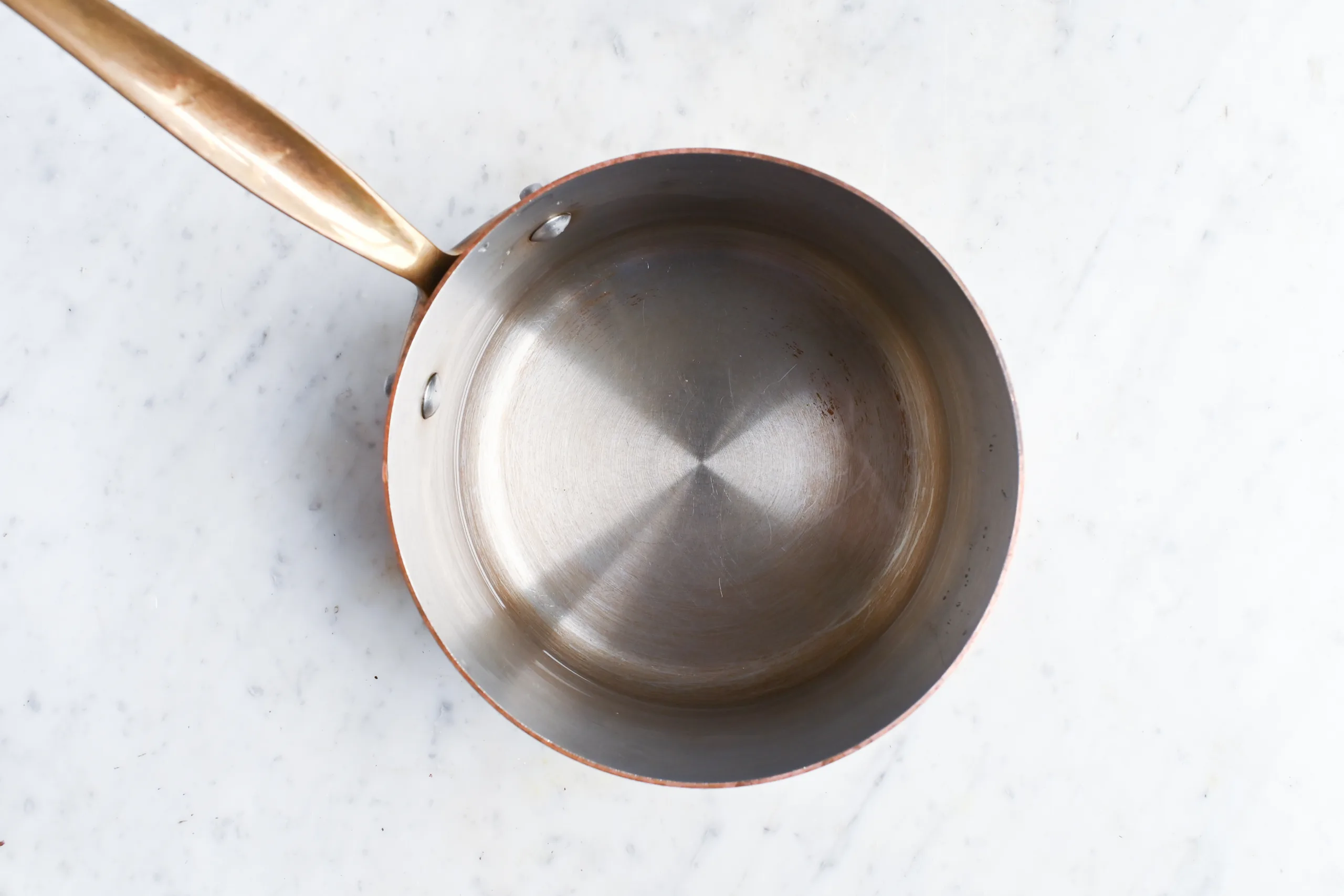 Water in a copper saucepan on a marble counter ready to simmer roasted dandelion roots for tea.