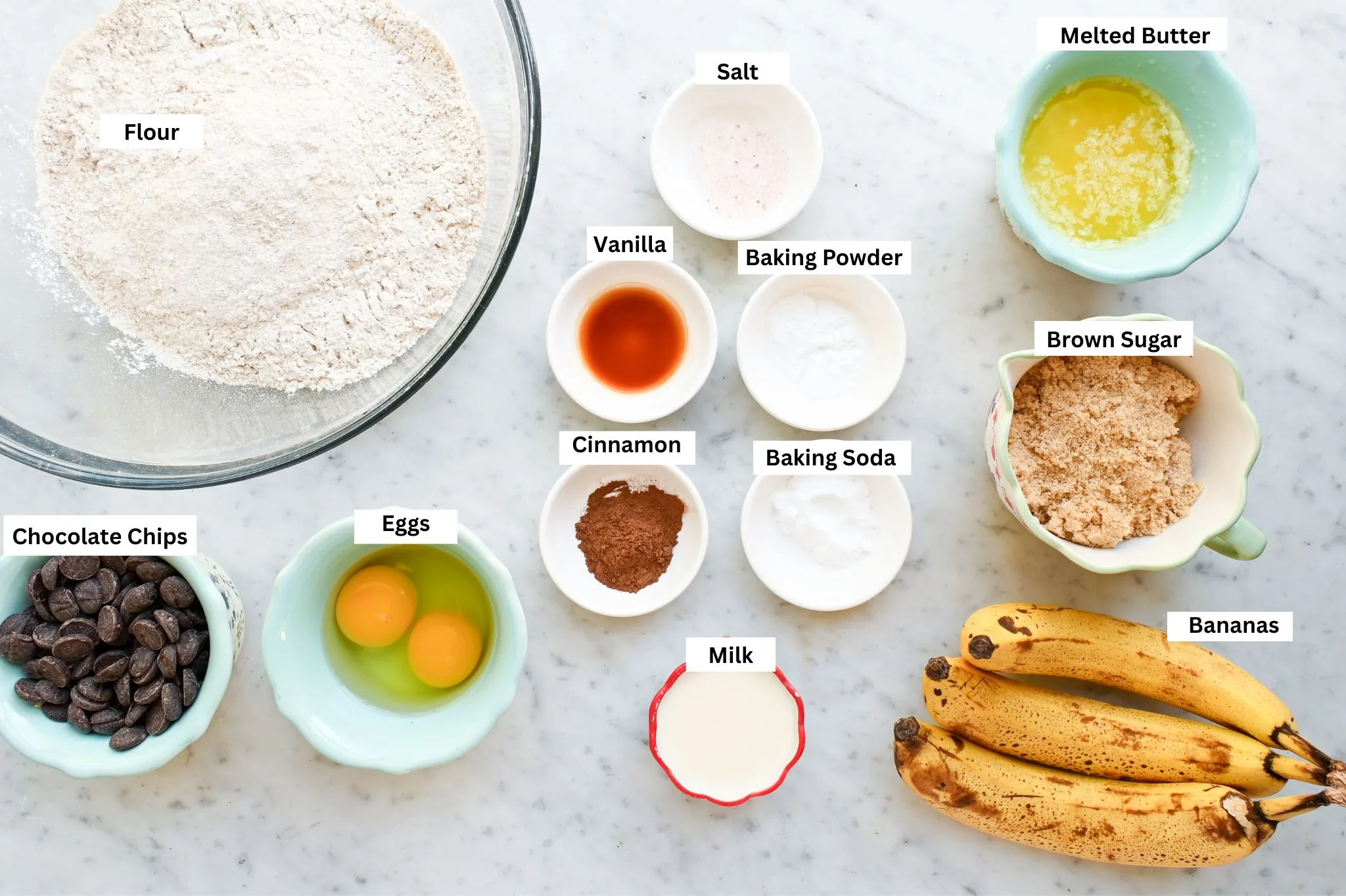 Ingredients for whole wheat banana muffins with chocolate chips, including fresh milled flour, ripe bananas, eggs, brown sugar, milk, butter, and chocolate chips.