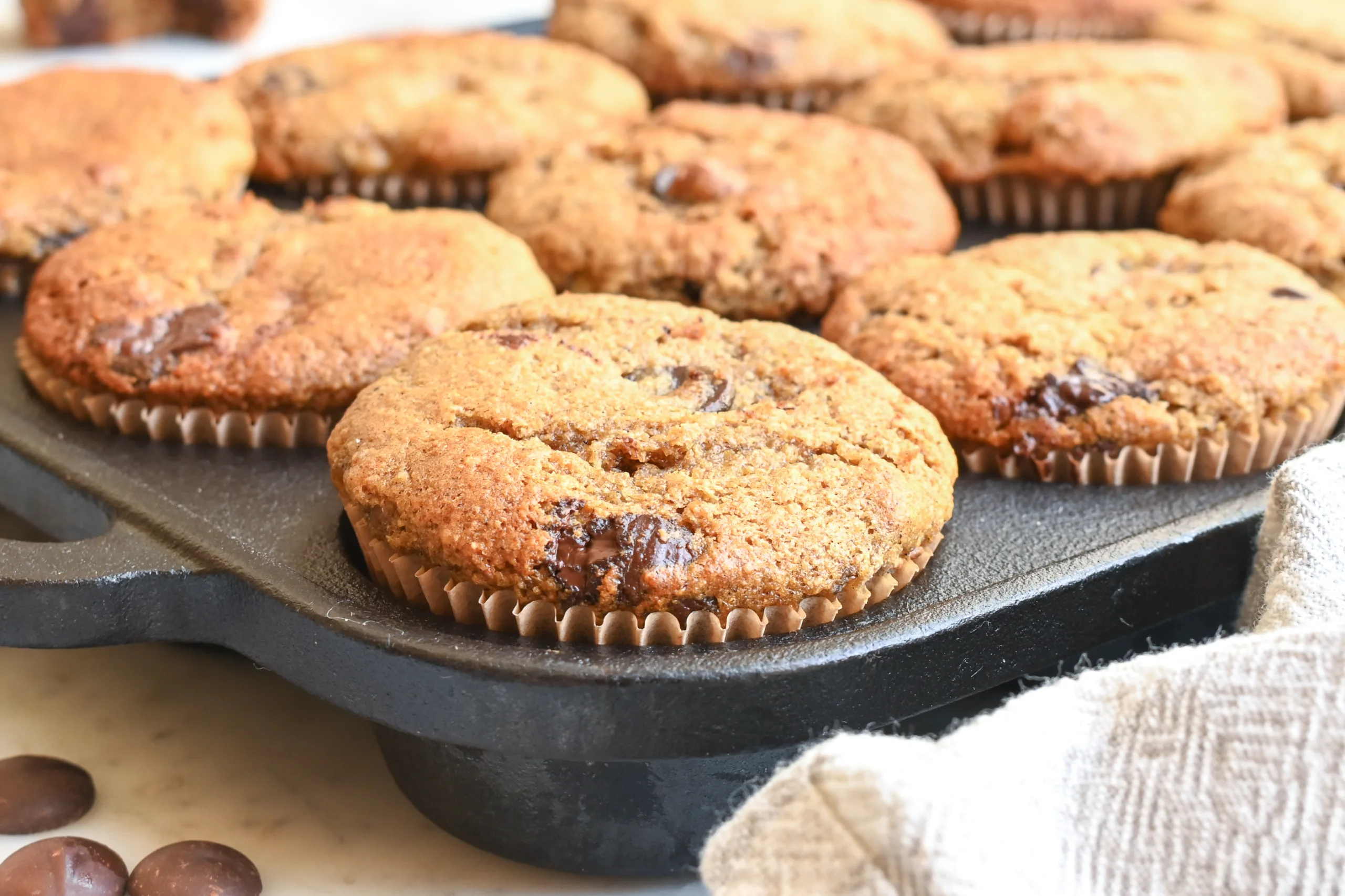 Fresh whole wheat banana muffins with chocolate chips showing a soft, moist center.