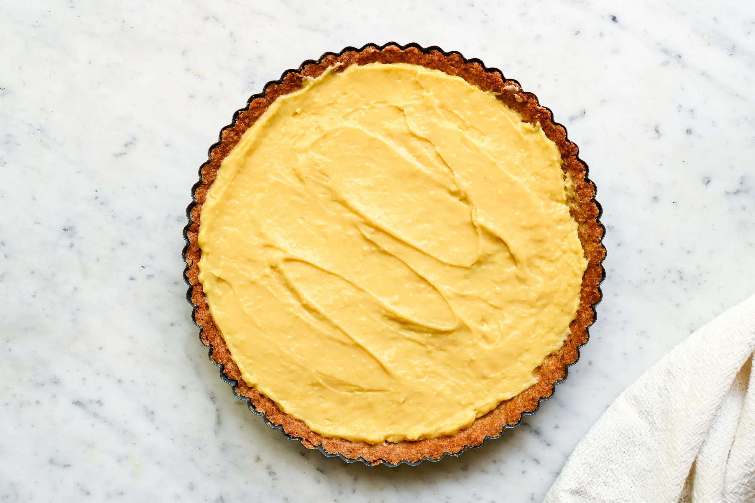 Thick vanilla cream filling spread inside a baked tart crust for a fresh berry cream tart.