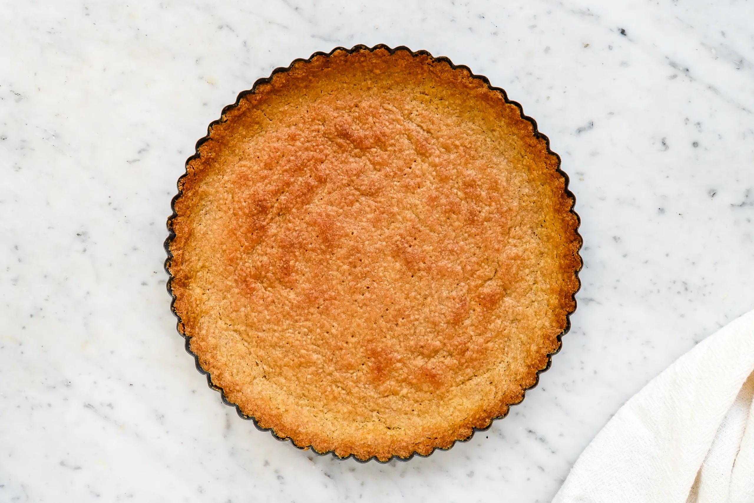 Baked fresh milled wheat tart crust in a fluted tart pan for an easy cream tart recipe.