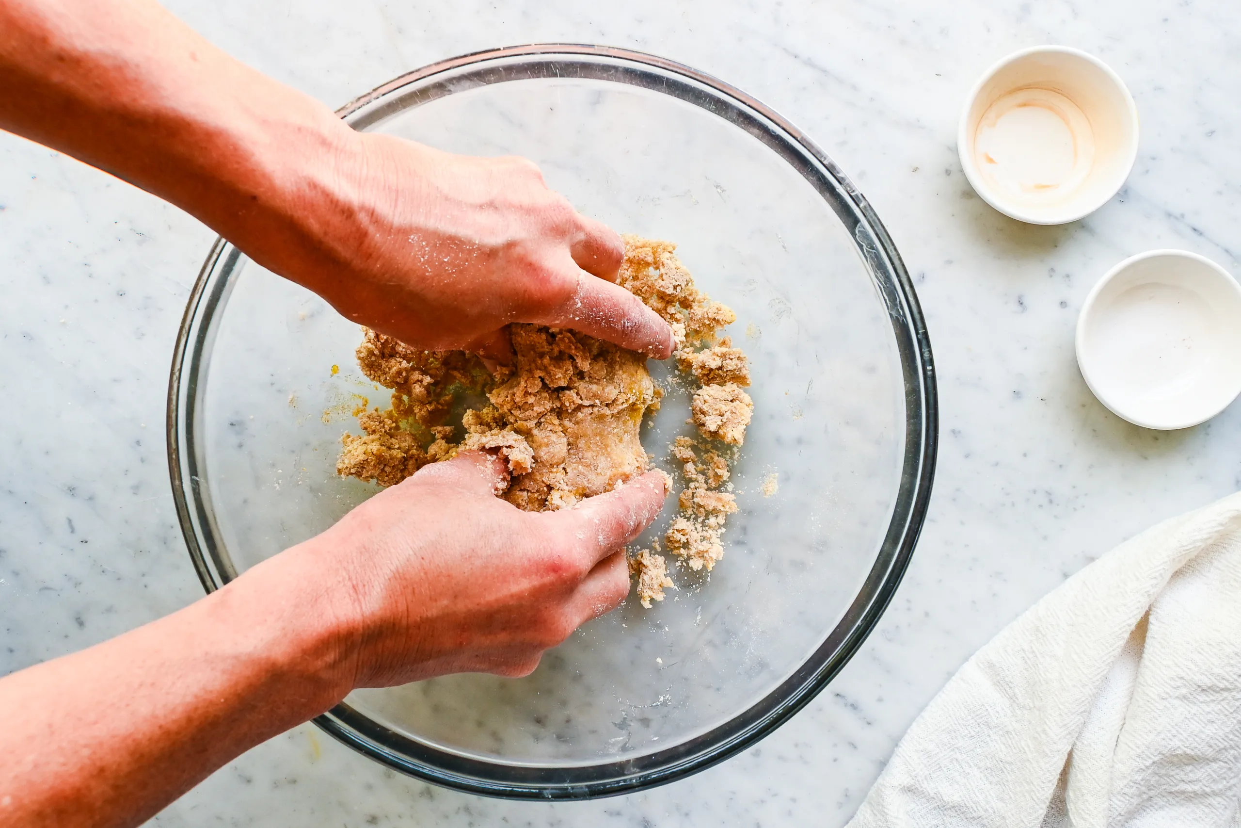 Hands bringing tart dough together before pressing it into the pan.