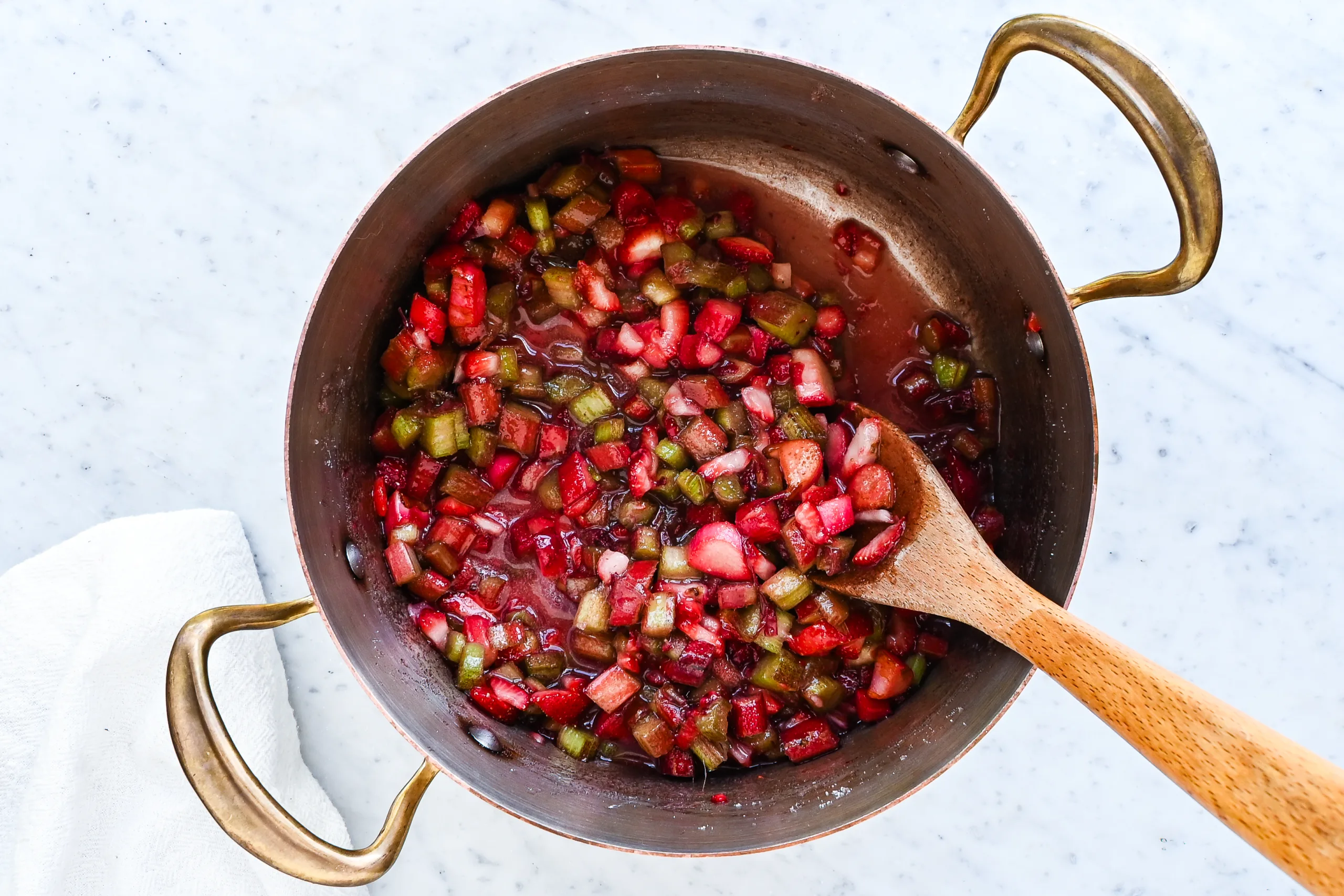 Strawberry and rhubarb mixture releasing juice as it begins to cook in a pot.