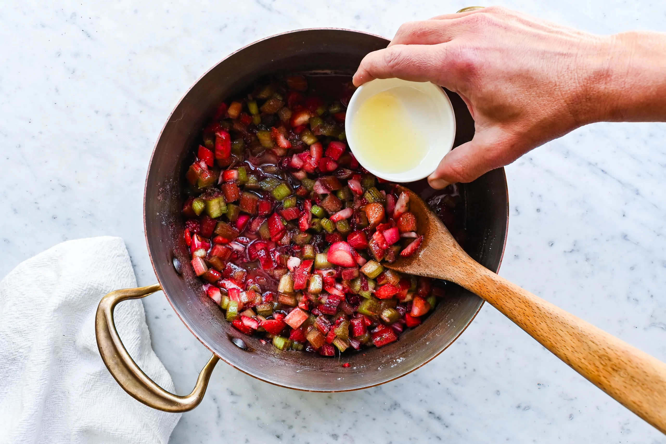 Fresh lemon juice being added to the strawberry and rhubarb jam mixture.