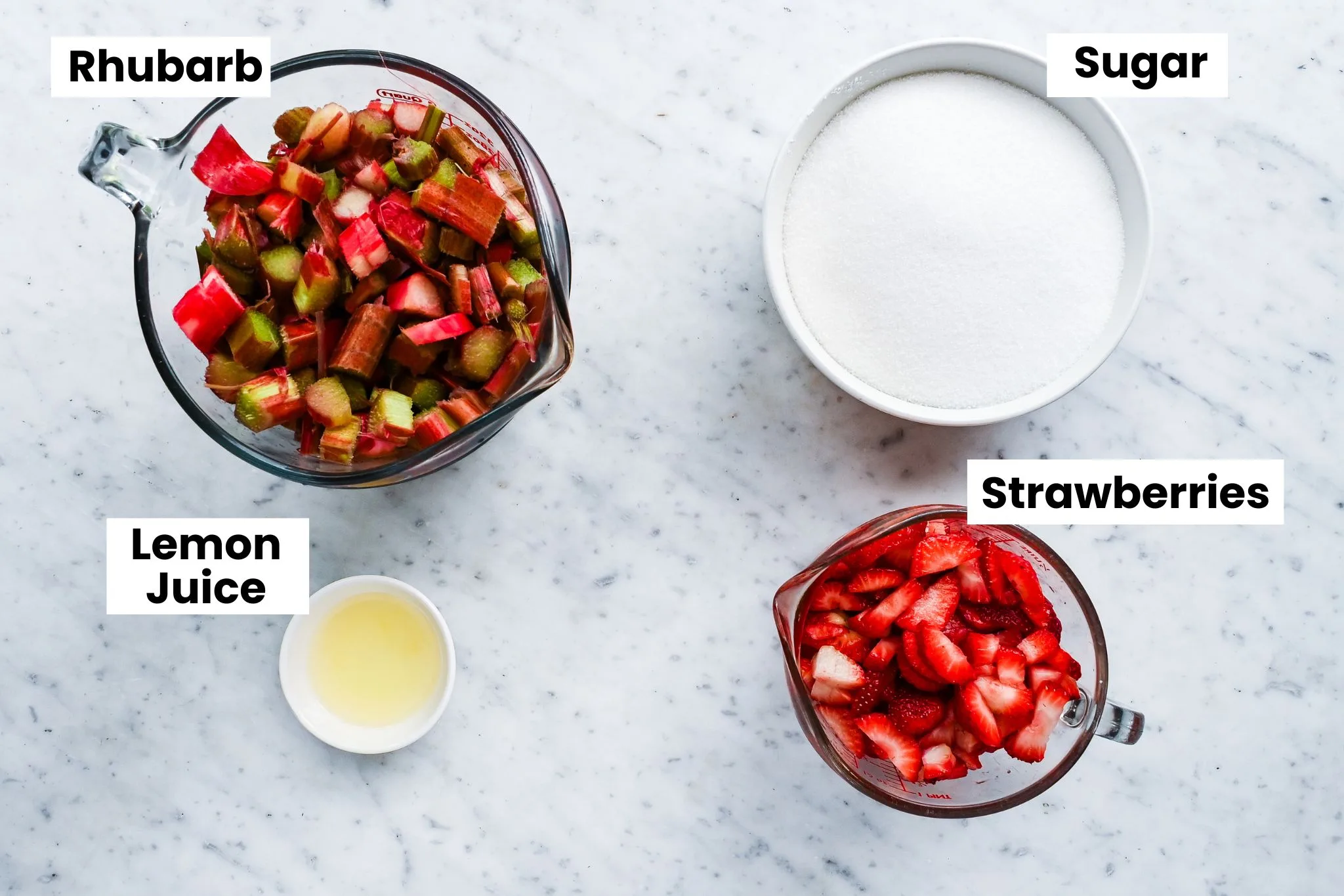 Chopped rhubarb, fresh strawberries, granulated sugar, and lemon juice arranged for strawberry rhubarb jam.
