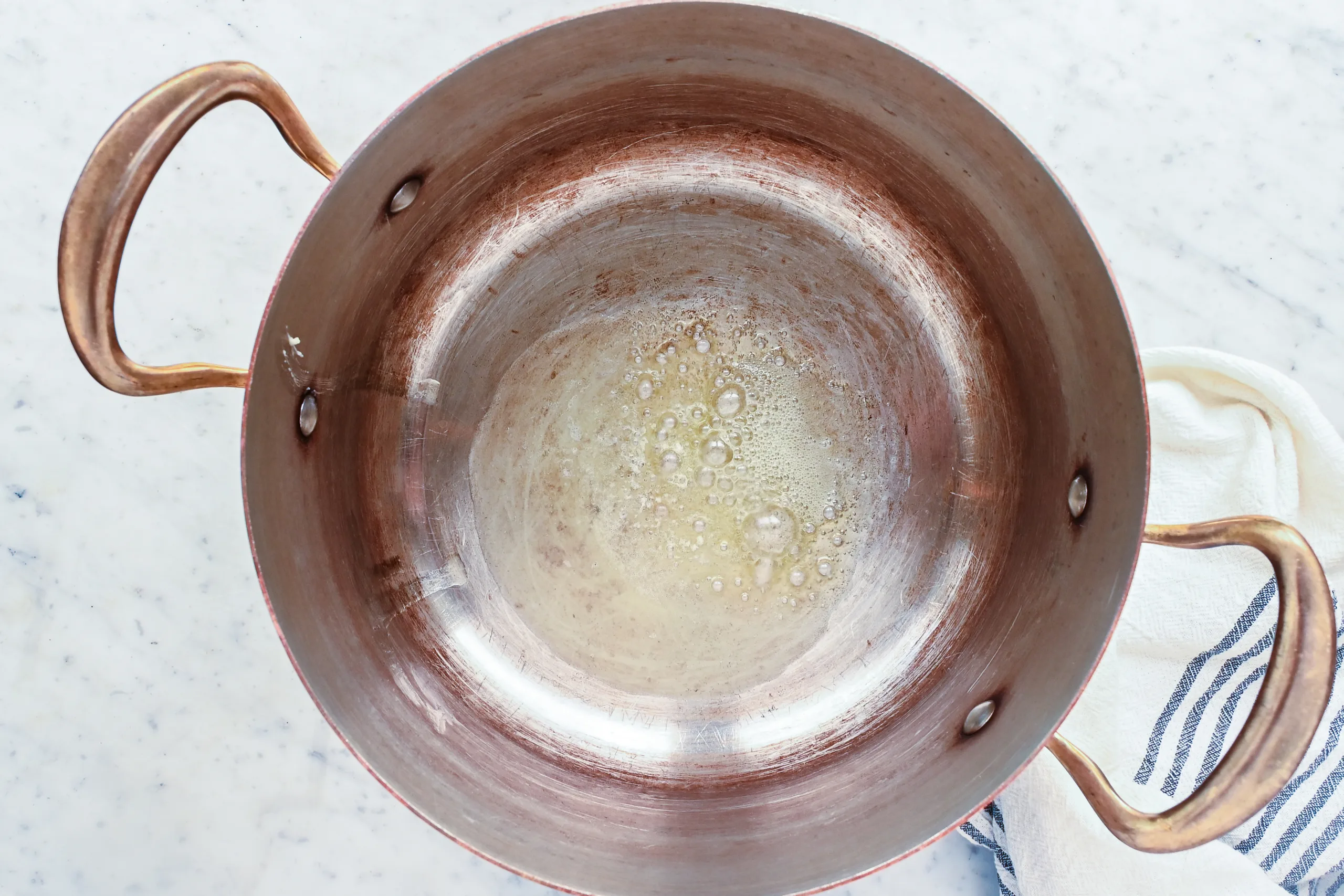 Butter melting in the bottom of a copper pot.