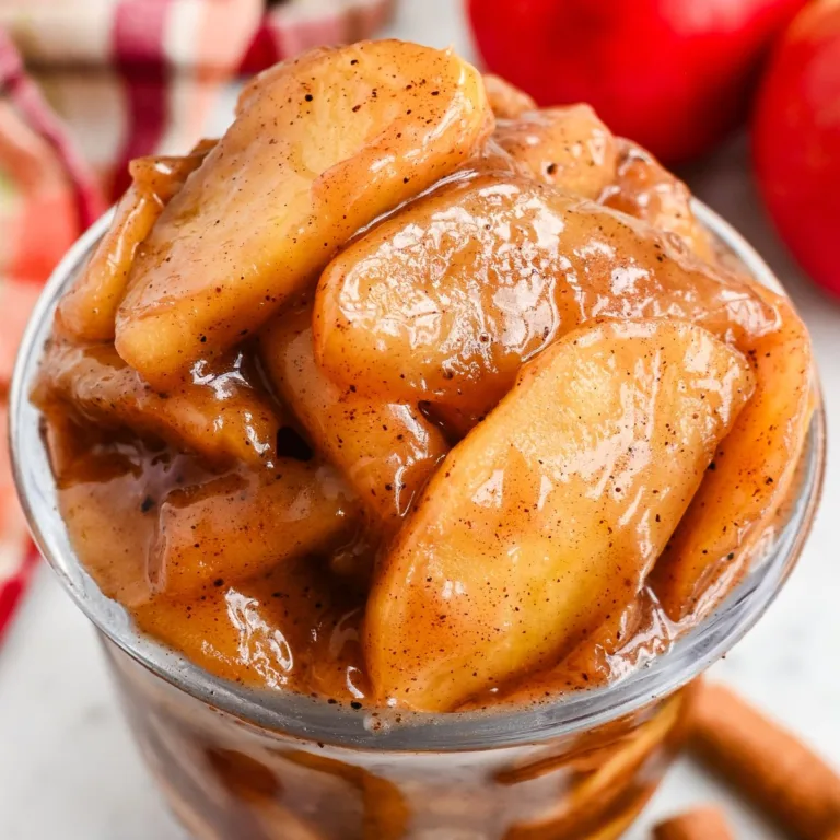 This close-up of homemade apple pie filling is the best choice for the feature image because it shows the finished recipe clearly. The glossy cinnamon-coated apples look rich and thick, and the fresh apples and cinnamon sticks in the background help readers instantly understand what the recipe is.