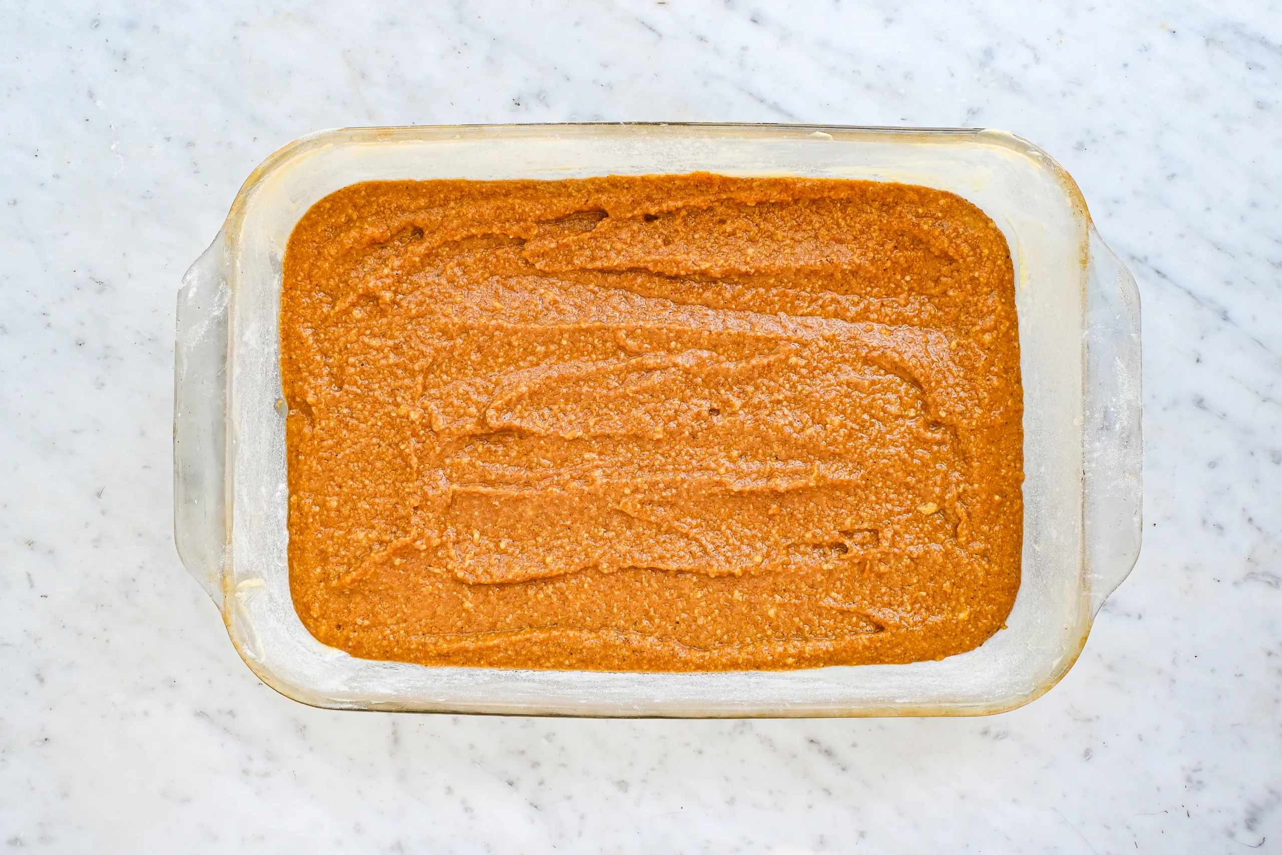 Pumpkin bar batter spread into a greased glass baking dish.