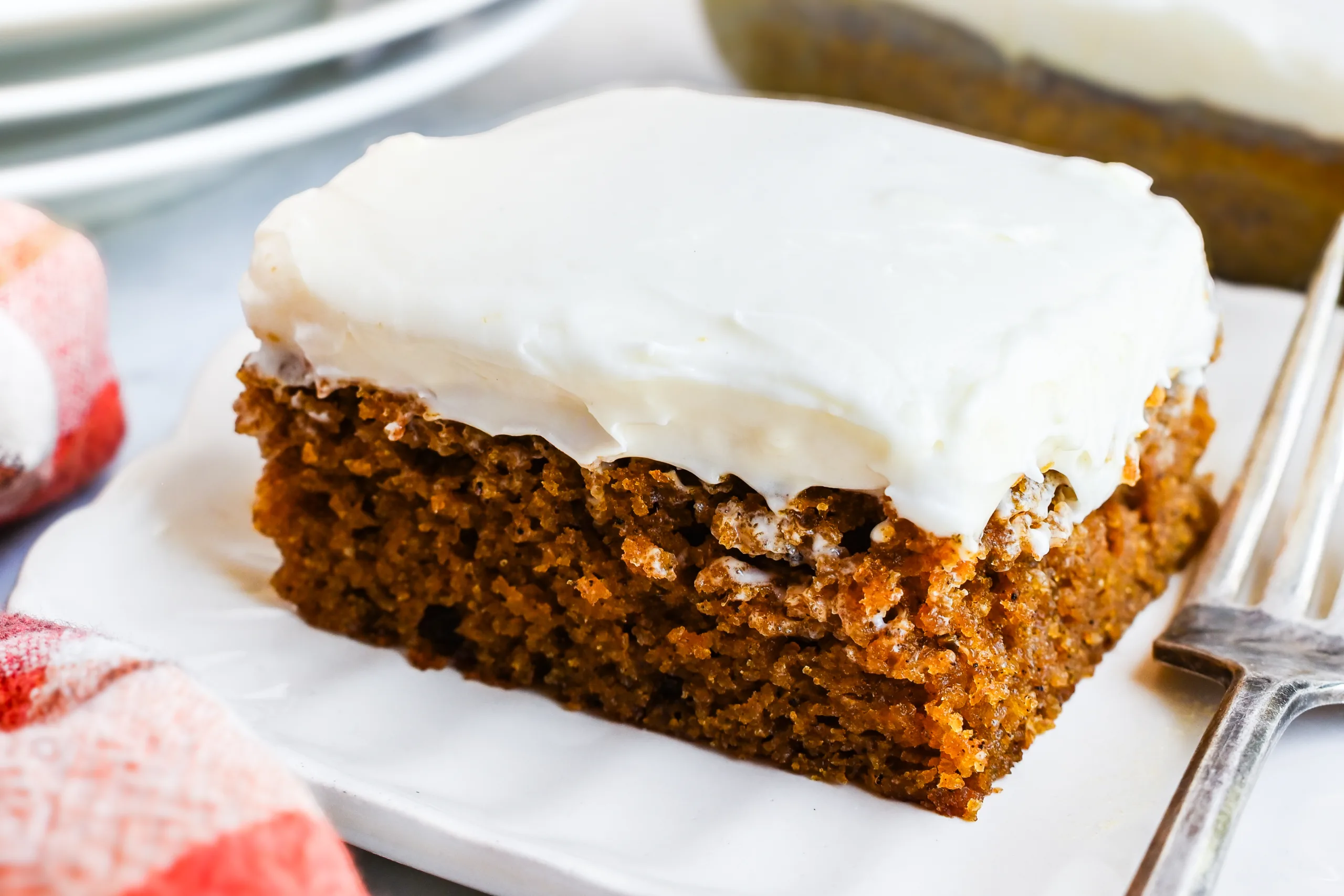 Close-up of a frosted pumpkin bar showing the moist pumpkin cake texture.