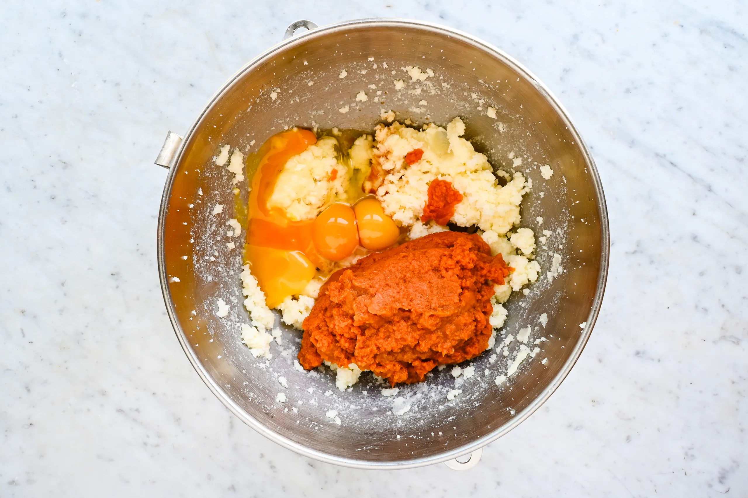 Pumpkin purée and eggs added to creamed butter and sugar in a stand mixer bowl.
