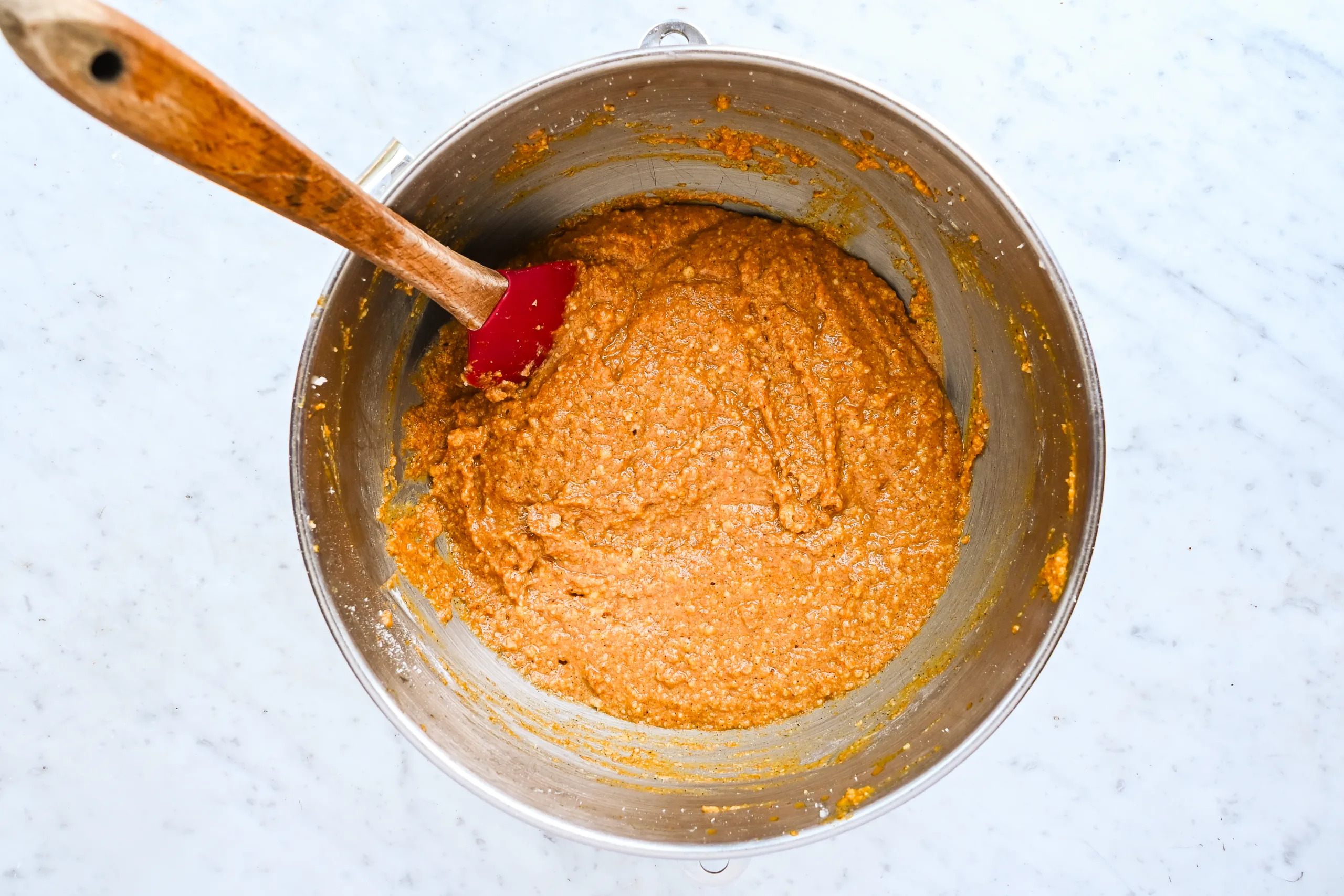 Pumpkin bar batter mixed in a stand mixer bowl with a red spatula.