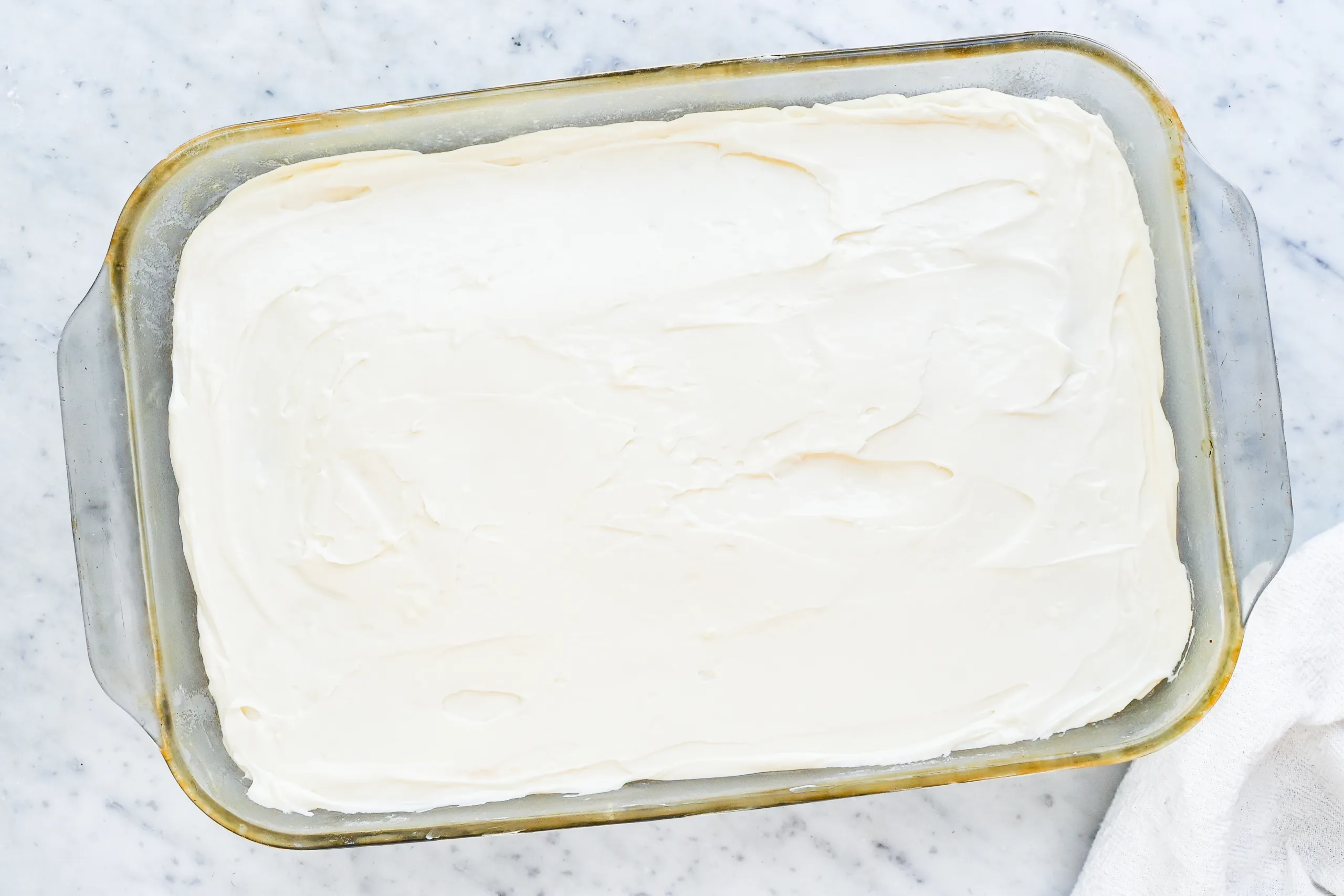 Pumpkin bars topped with cream cheese frosting in a glass baking dish.