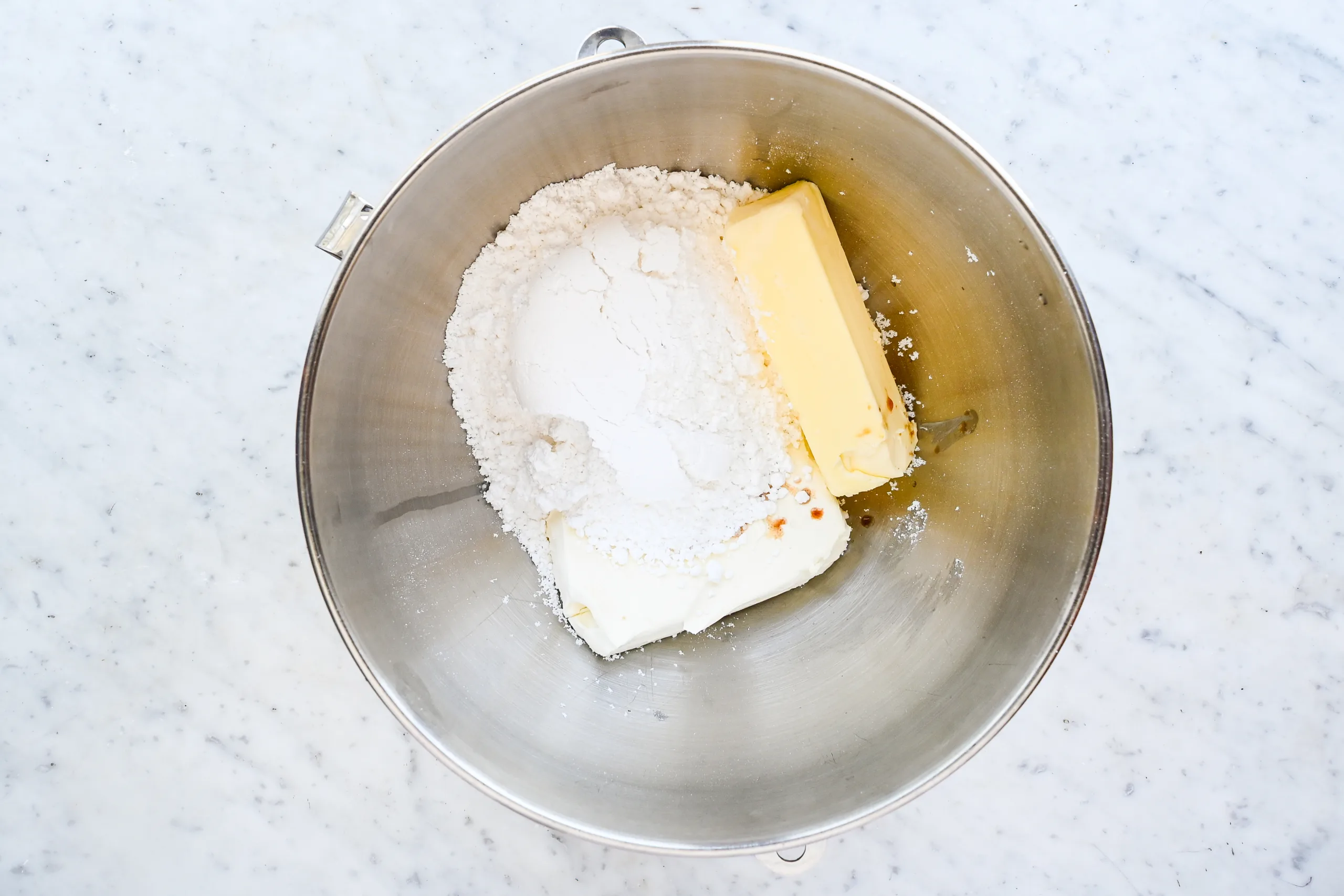 Cream cheese, butter, powdered sugar, and vanilla in a stand mixer bowl for frosting.