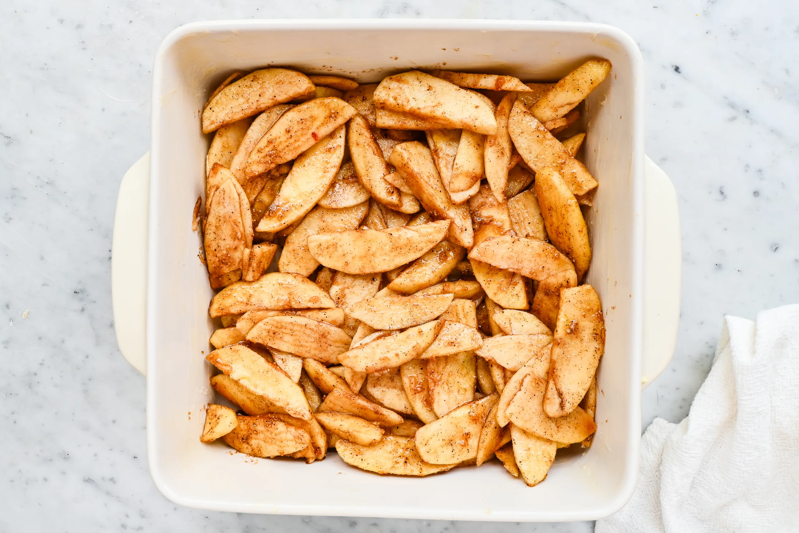 Cinnamon apple filling spread in a white baking dish.