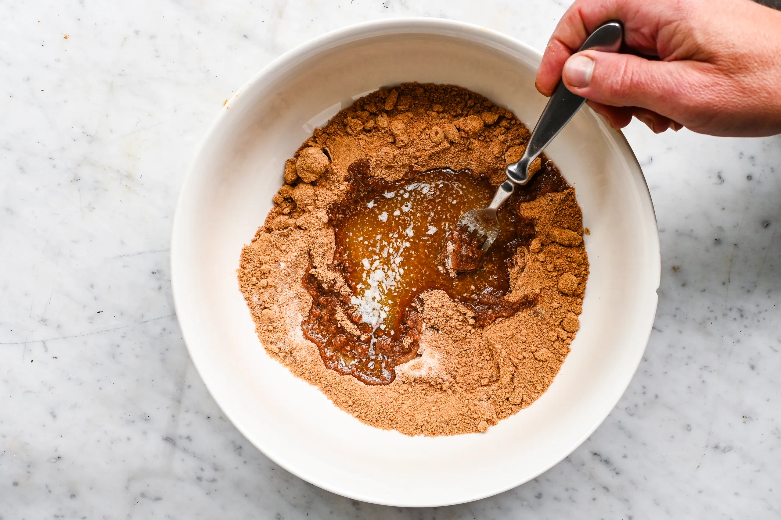 Melted butter being mixed into graham cracker crumbs and sugar for a homemade pie crust.