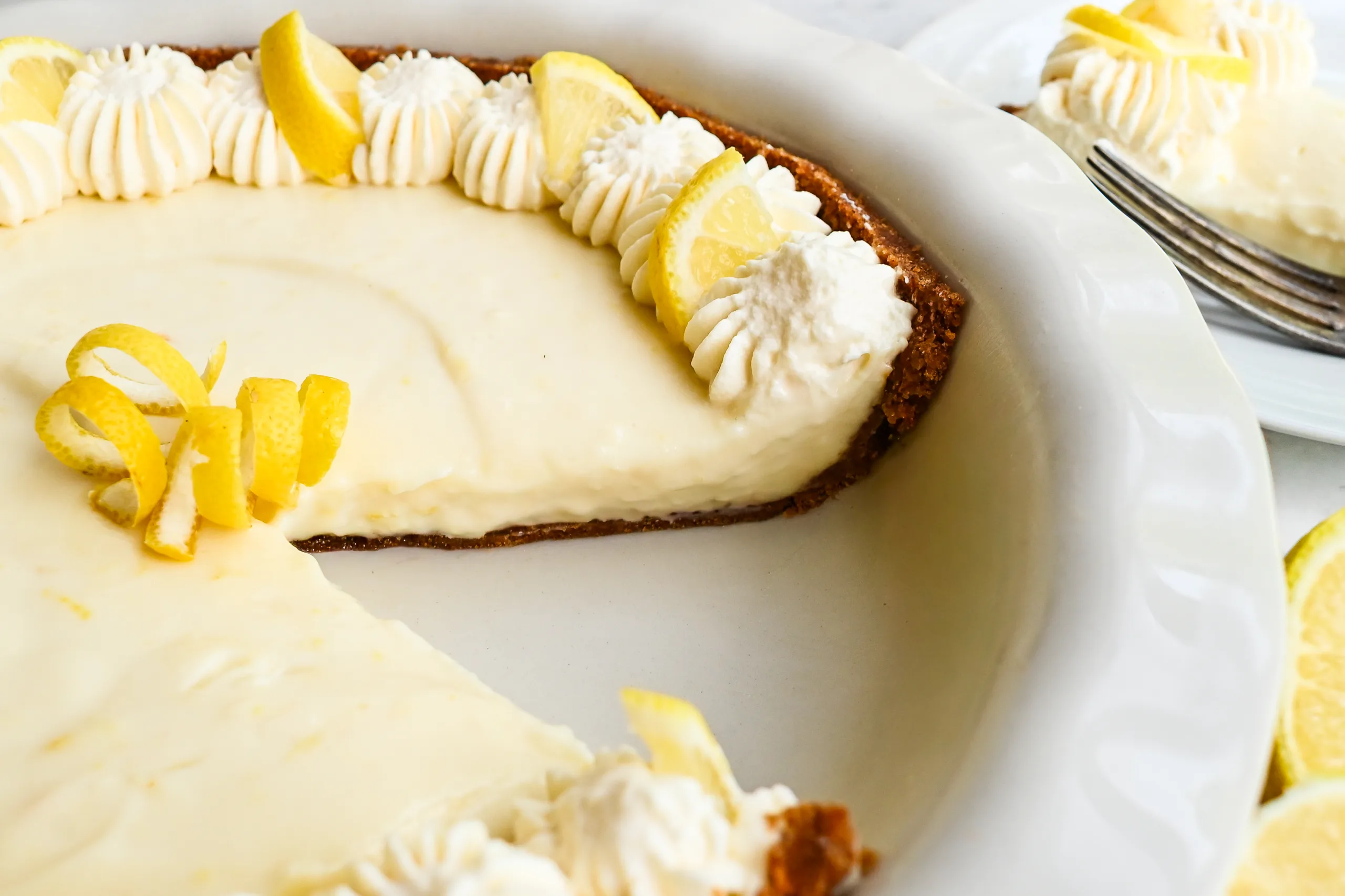 Close-up of no-bake lemon icebox pie showing the creamy lemon filling, graham cracker crust, whipped cream, and lemon garnish.
