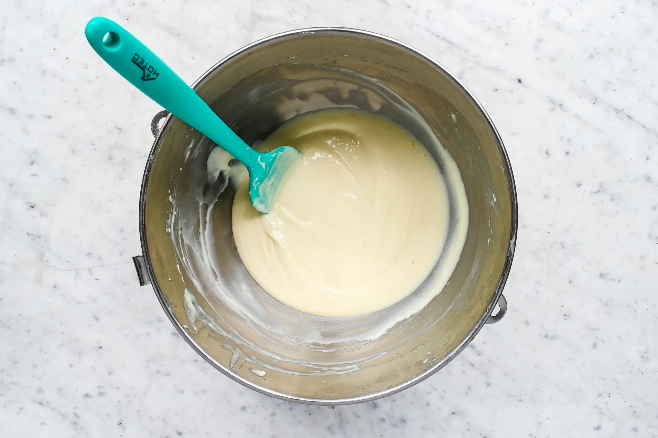 Smooth lemon icebox pie filling mixed in a stand mixer bowl with a spatula.