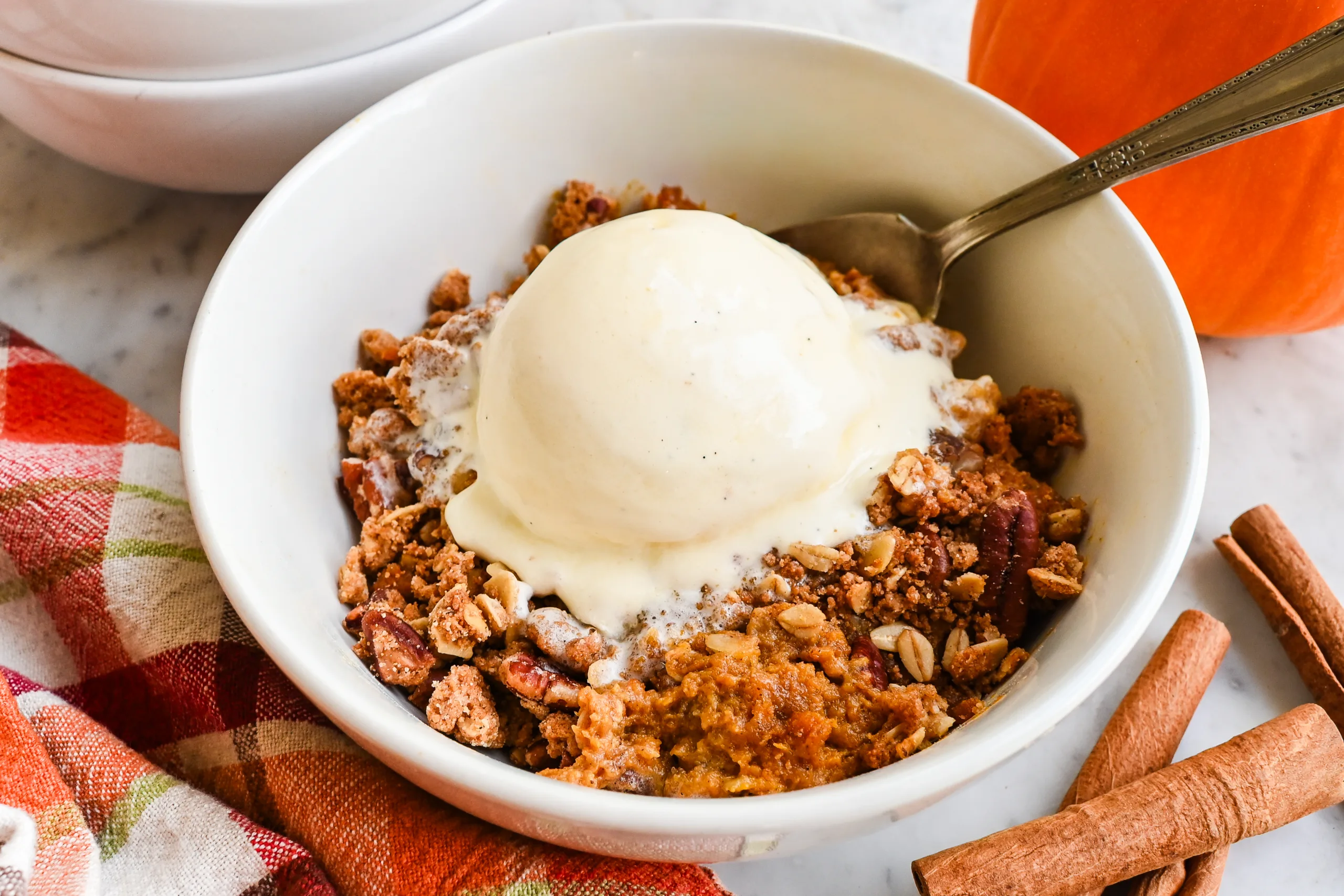 Pumpkin crisp topped with oat pecan crisp topping in a glass baking dish before baking.