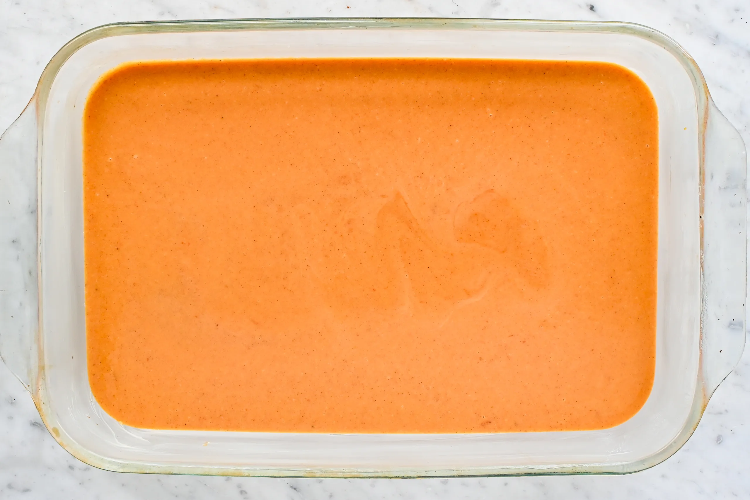 Smooth pumpkin crisp filling poured into a greased glass baking dish.