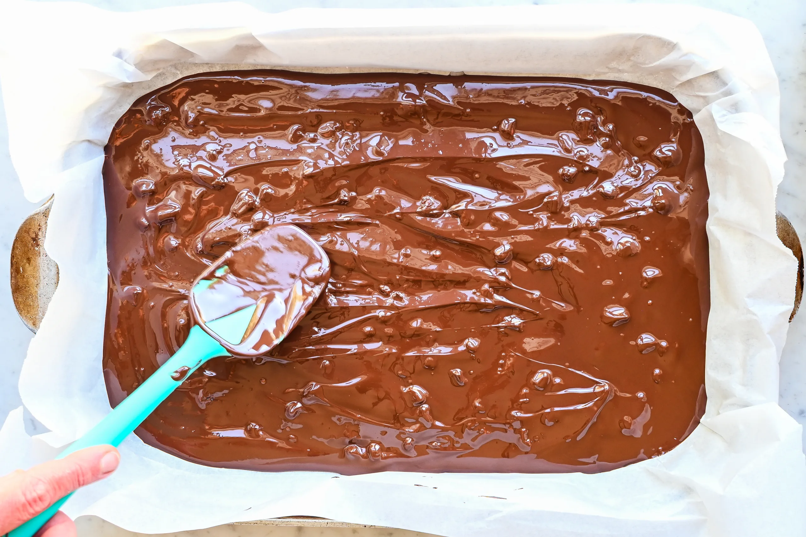Melted dark chocolate spread into a parchment-lined baking pan.