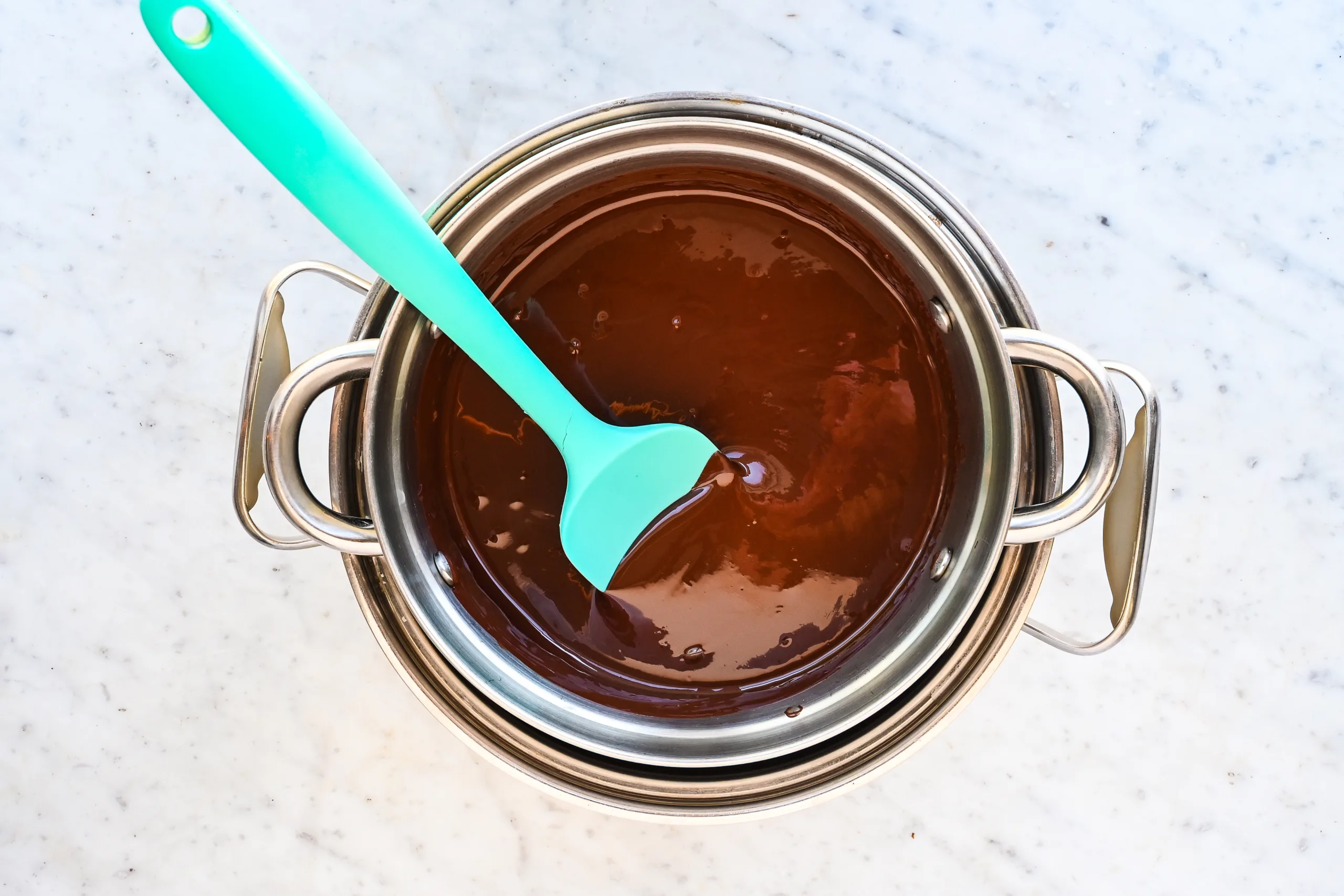 Melted dark chocolate stirred with a spatula in a double boiler.