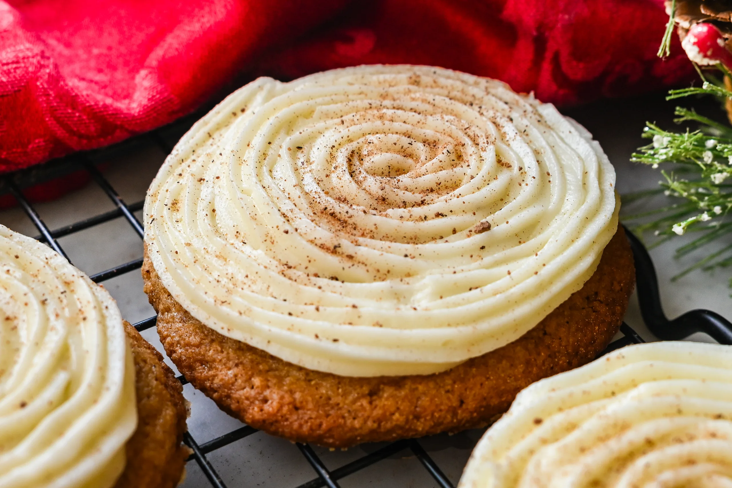 Close-up of a soft eggnog cookie topped with cream cheese frosting and a sprinkle of nutmeg.