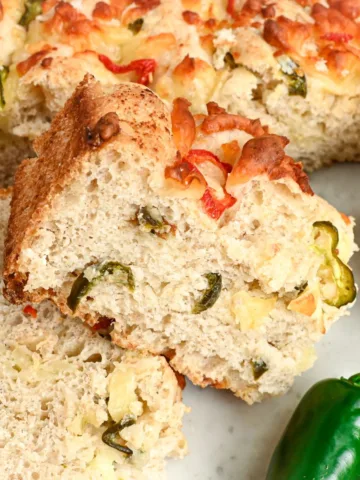 Side view of sliced jalapeño cheddar sourdough focaccia showing the soft inside, melted cheese, and jalapeños throughout.