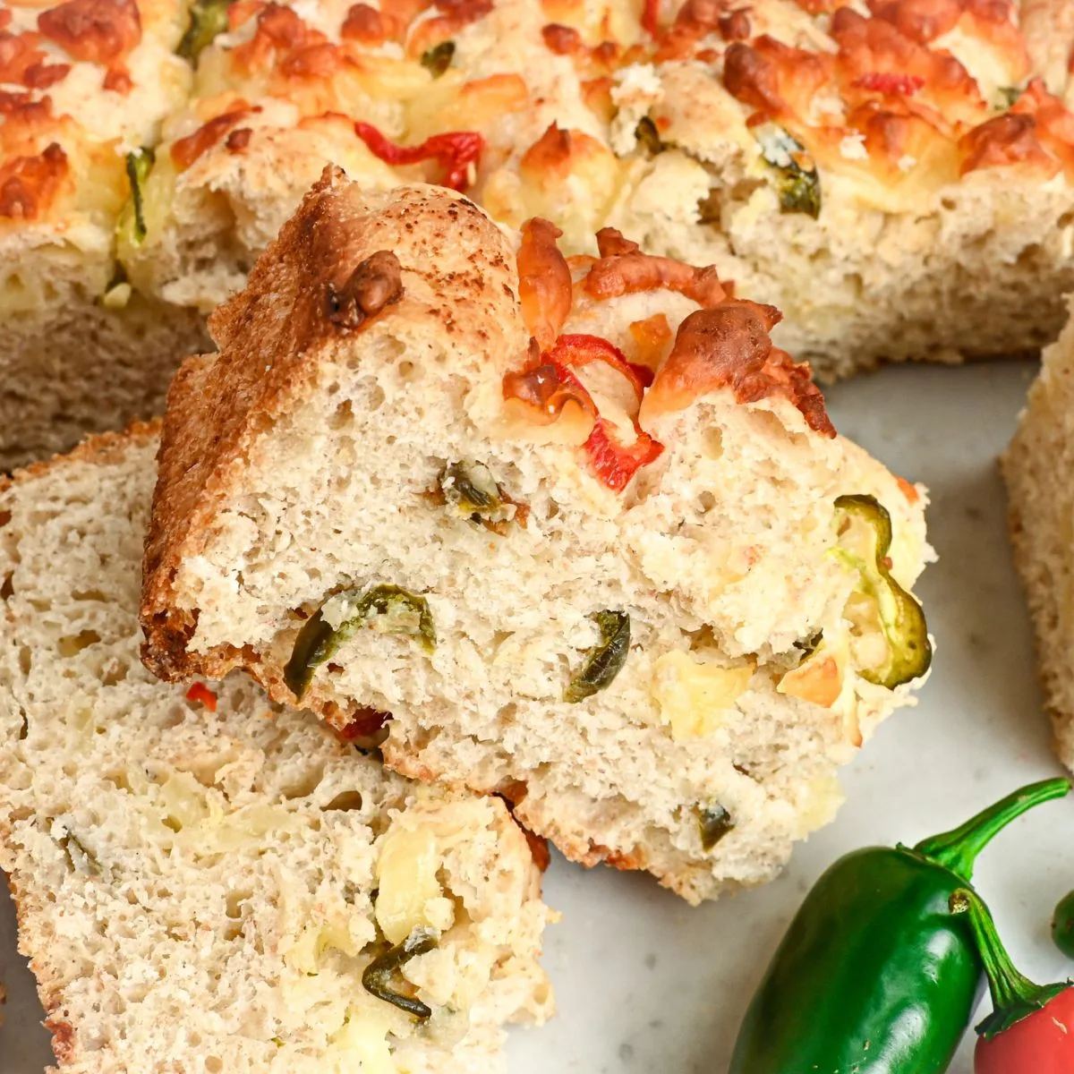 Side view of sliced jalapeño cheddar sourdough focaccia showing the soft inside, melted cheese, and jalapeños throughout.