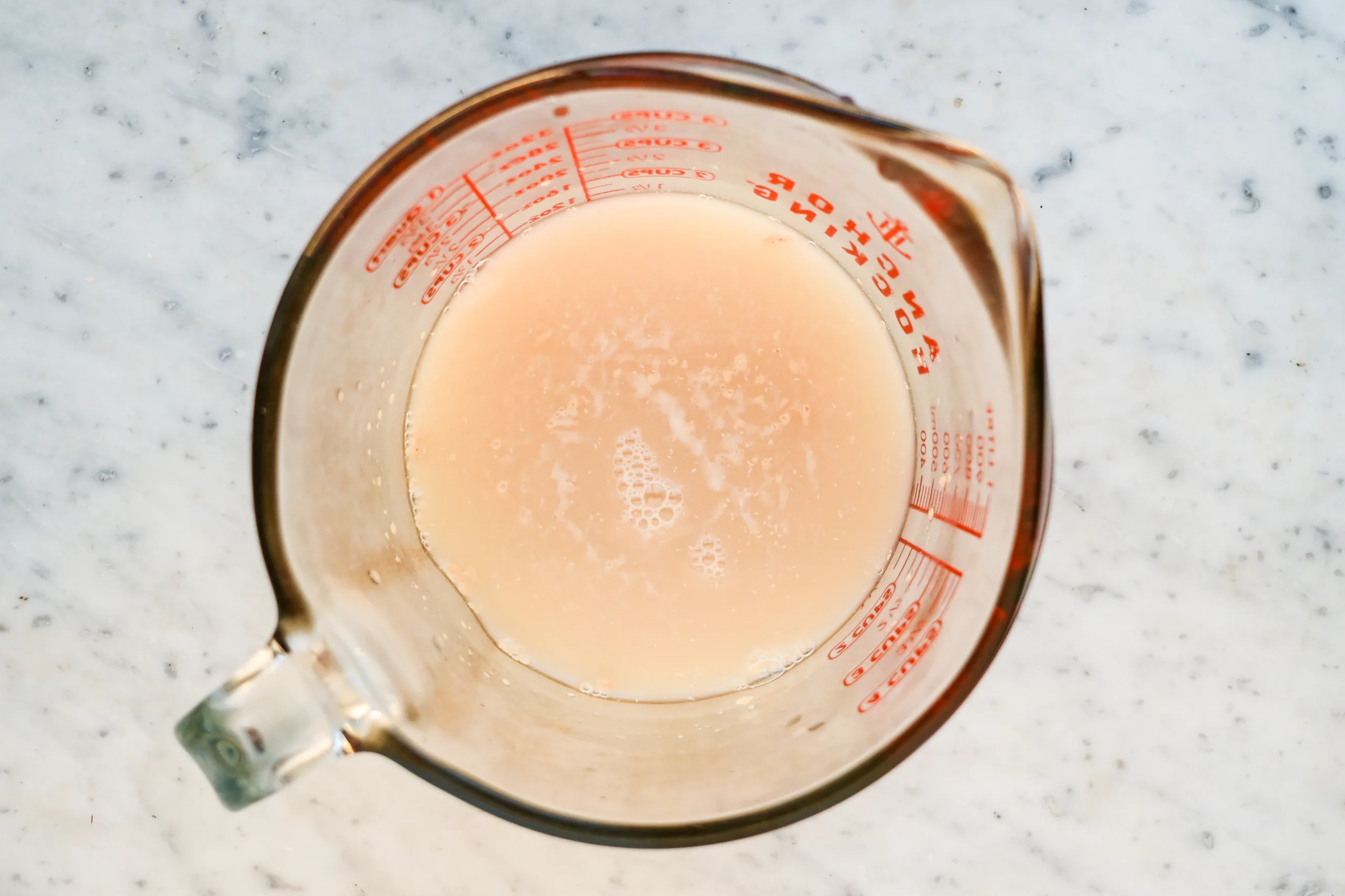 Yeast being proofed in a measuring cup for lemon blueberry sourdough focaccia.