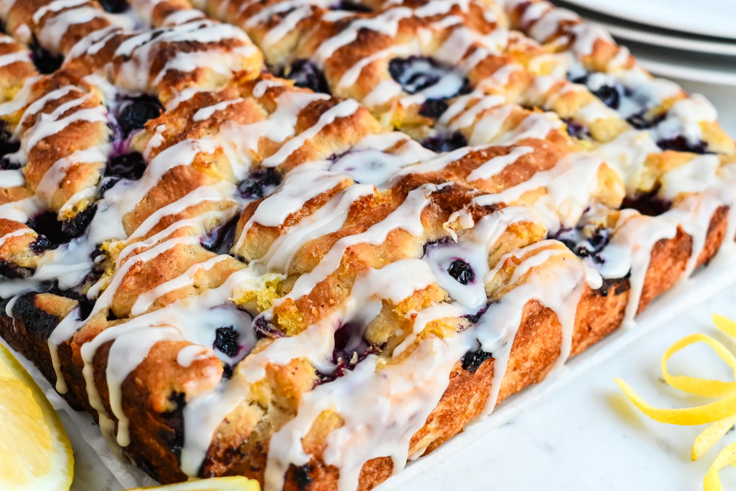 Close-up of lemon blueberry sourdough focaccia showing the golden crust, blueberries, and lemon glaze.