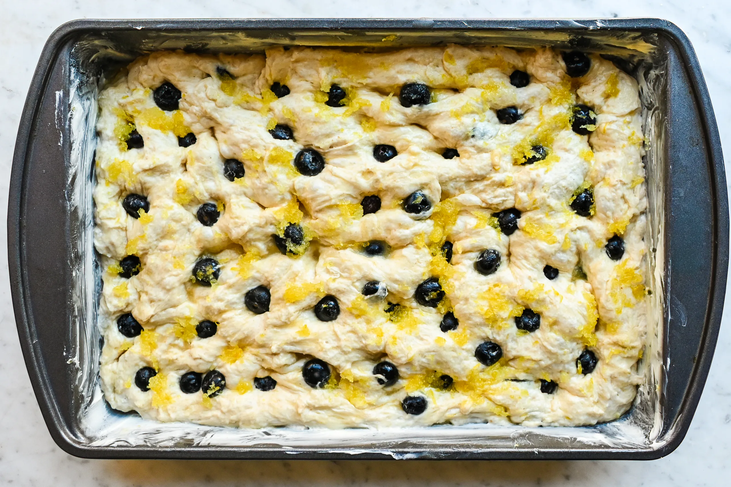 Lemon rind mixed with sugar has been spread across the focaccia dough, ready to bake.