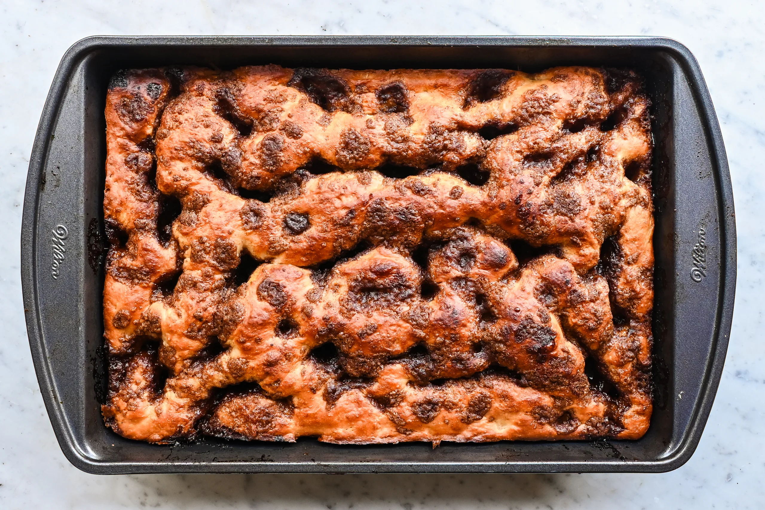 Baked cinnamon roll focaccia in a 9x13-inch pan with golden brown cinnamon sugar topping.