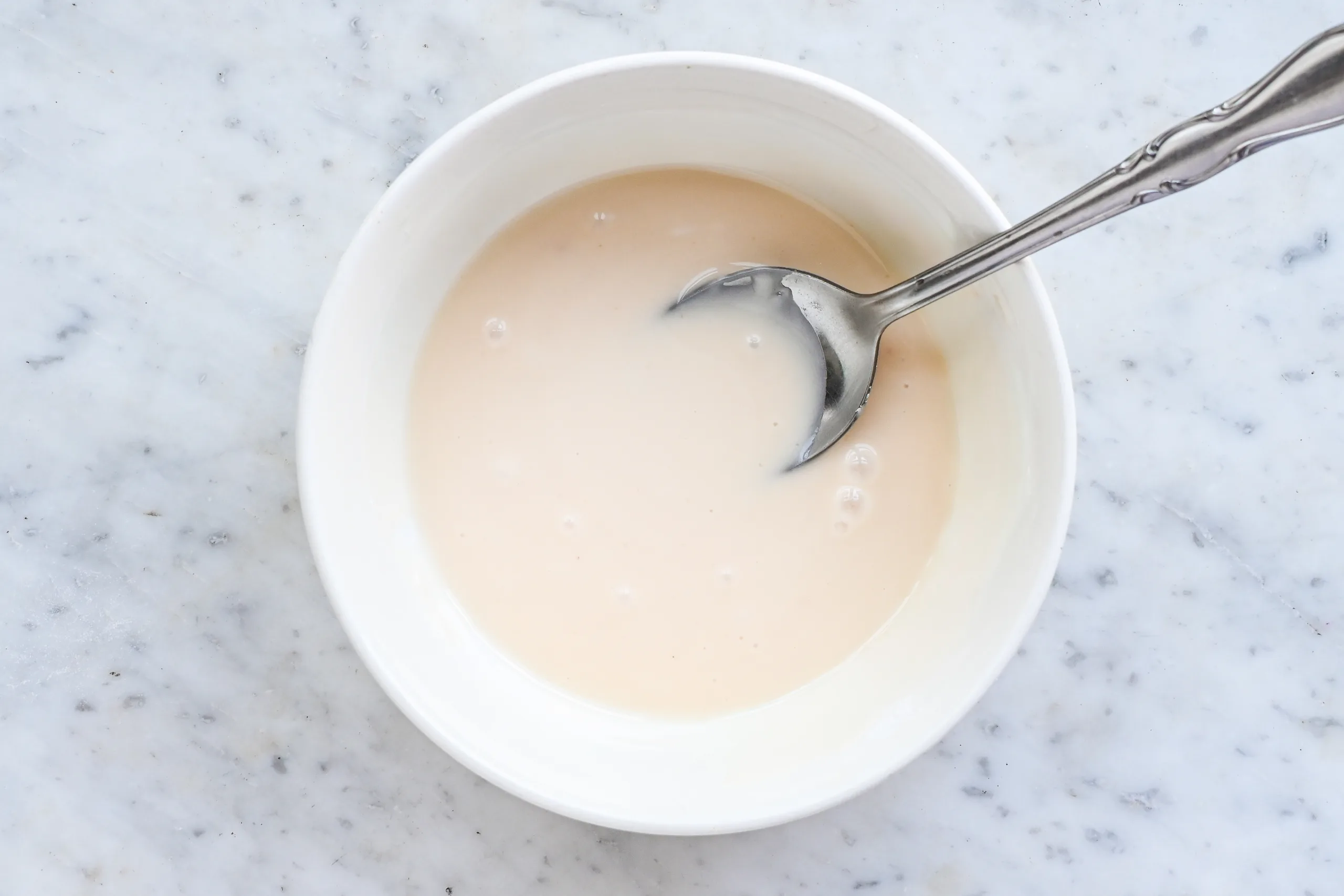 Vanilla glaze mixed in a white bowl with a spoon.