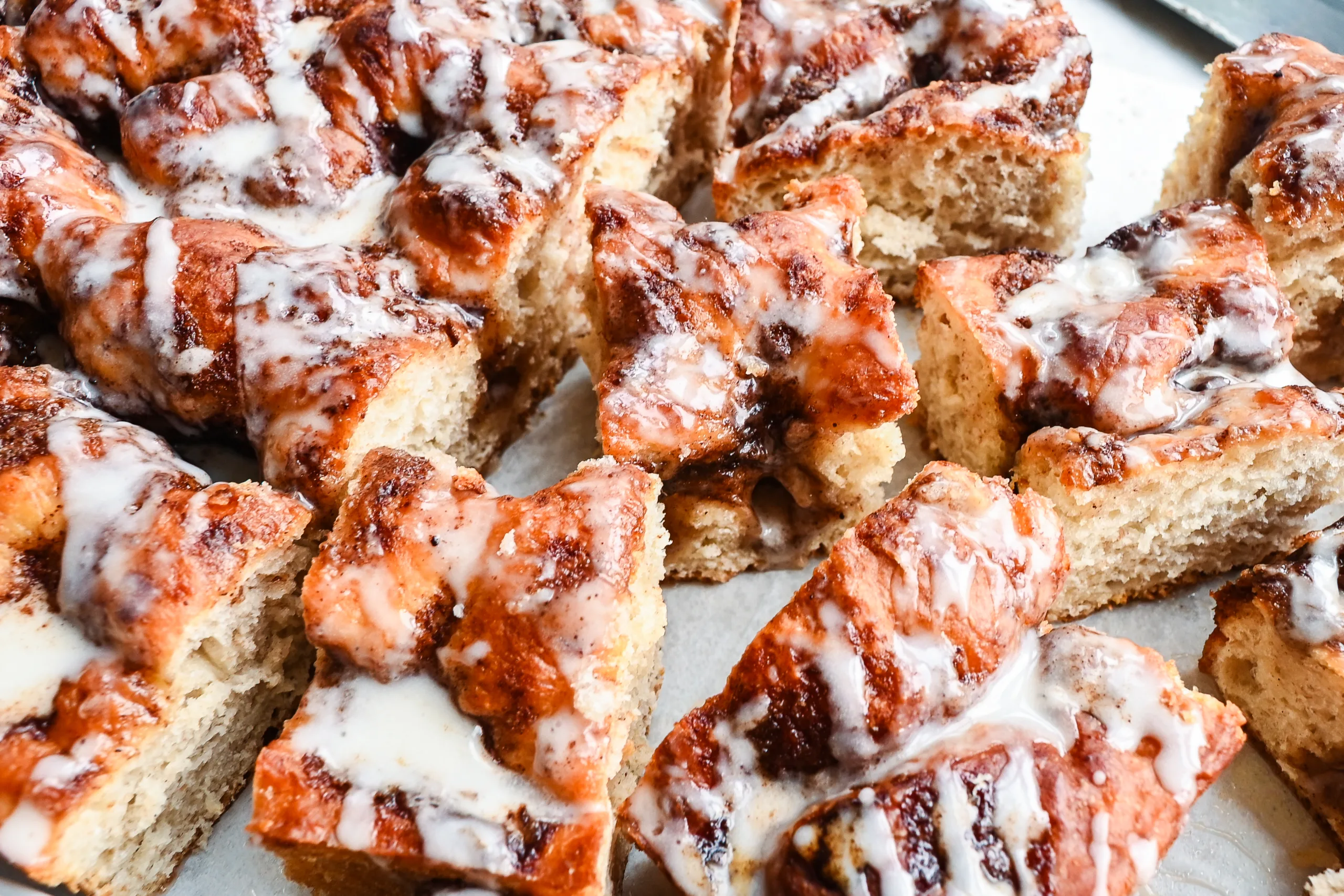 Sliced sourdough discard cinnamon roll focaccia showing the soft crumb, cinnamon sugar pockets, and vanilla glaze.