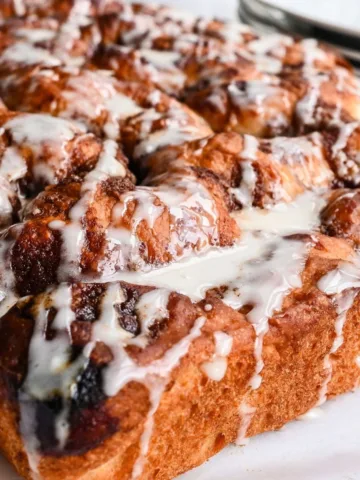 Sourdough discard cinnamon roll focaccia with cinnamon sugar pockets and vanilla glaze on top.
